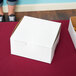 A white pie / bakery box on a red table.