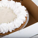 A pie in a 9" x 9" white bakery box with whipped cream on top.
