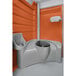 An orange PolyJohn portable restroom with a sink and toilet seat.