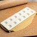 A white plastic Fox Run Ravioli Maker with dough with holes in it.