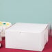 A white customizable cake box on a red surface.