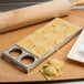 A metal tray with ravioli and a rolling pin.