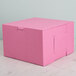 A pink bakery box with a lid on a marble surface.