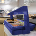 A navy blue Cambro buffet with a free standing sneeze guard filled with food.