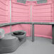 A pink and grey PolyJohn wheelchair accessible portable restroom.