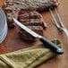A steak on a cutting board with a Mercer Culinary serrated steak knife.