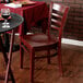 A Lancaster Table & Seating mahogany wood chair with a mahogany wood seat next to a table with a glass of wine.