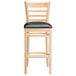A Lancaster Table & Seating wooden bar stool with a black vinyl seat on a white background.