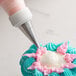 A person using an Ateco leaf piping tip on a pastry bag to frost a cupcake.