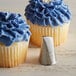A cupcake with blue frosting piped with Ateco Korean flower design.