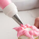 A person using an Ateco leaf piping tip to decorate a cupcake with a pastry bag.