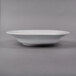A white Libbey Lunar Bright porcelain soup bowl with a black rim on a gray surface.