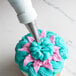 A cupcake with blue and pink frosting piped with an Ateco small curved petal piping tip.