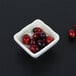 A Van Gogh taupe square melamine ramekin filled with cranberries.