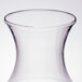 A clear plastic WNA Comet disposable wine carafe with a small amount of liquid in it.