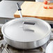 A Vollrath Wear-Ever aluminum pot cover on a large pan on a stove.