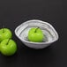 An Elite Global Solutions black oval melamine bowl filled with green apples.