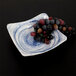 A white square melamine bowl with a blue and white Van Gogh design filled with grapes.