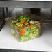 A Cambro amber plastic food pan filled with broccoli and carrots.