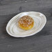 An Elite Global Solutions taupe melamine oval plate with a small round pastry on it.