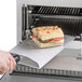 A sandwich being made on a metal plate in an ACP XpressChef 3i MRX2 high-speed countertop oven.