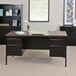 A black Hirsh Industries double pedestal desk with a walnut top.