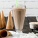 A glass of J. Hungerford Smith chocolate milkshake with a straw and marshmallows.
