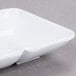 A white square GET Water Lily melamine sauce dish with two sections.