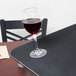 A glass of red wine sits on a Carlisle non-skid serving tray on a table in a fine dining restaurant.