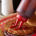 A hamburger with ketchup in a Vollrath Twin Tip squeeze bottle.