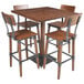 A Lancaster Table & Seating live edge wood bar table with four barstools around it.