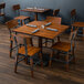 A Lancaster Table & Seating solid wood table and chairs with an antique walnut finish on a table in a farm-to-table restaurant.