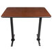 A Lancaster Table & Seating bar height table with a black base and a reversible wood table top with brown and oak sides.