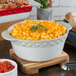 A white Tuxton round casserole dish filled with macaroni and cheese.