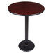 A Lancaster Table & Seating bar height table with a black pole and a round cherry table top.
