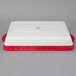 A white and red rectangular casserole dish with a Tuxton logo.