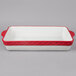 A white rectangular Tuxton China casserole dish with red handles.