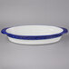 A white oval casserole dish with a blue rim.