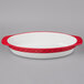 A white oval casserole dish with a red rim.