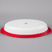 A white oval china casserole dish with a red and white lid.