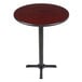 A Lancaster Table & Seating bar height table with a 30" round cherry wood and black table top on a cast iron base.