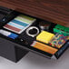 A desk drawer with stationery and pens, including a spiral bound notebook.