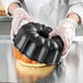 A person in gloves holding a Chicago Metallic fluted bundt cake.