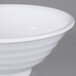 A close-up of a white Carlisle Terra melamine footed bowl with a white rim.