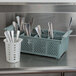 A Noble Products metal flatware rack with spoons and forks in it on a counter.