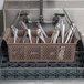 A brown Noble Products flatware rack with spoons in it.