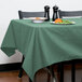 A table with a seafoam green Intedge tablecloth and a plate of food.
