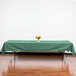 A rectangular seafoam green Intedge table cover on a table with flowers.