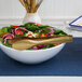 A bowl of salad with a pair of gold tongs.