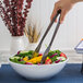 A person using American Metalcraft wavy stainless steel tongs to serve vegetables from a bowl.